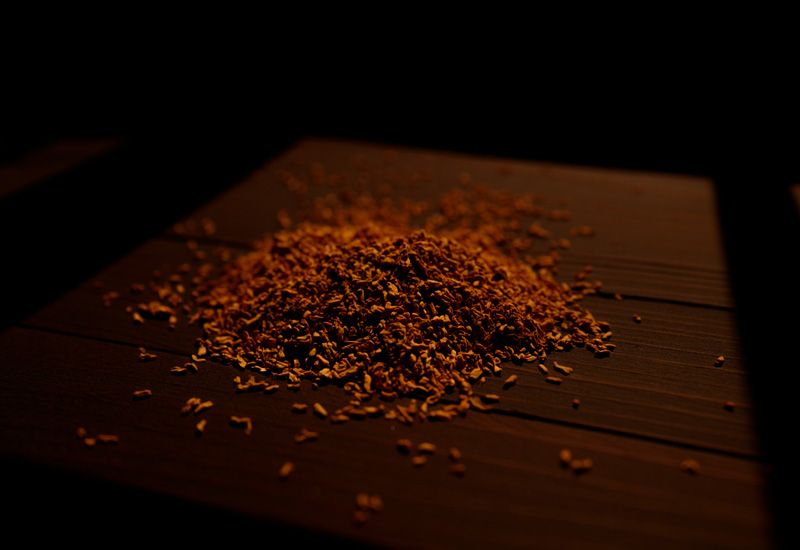 Кучка измельчённой травяной смеси лежит в центре тёмного деревянного стола